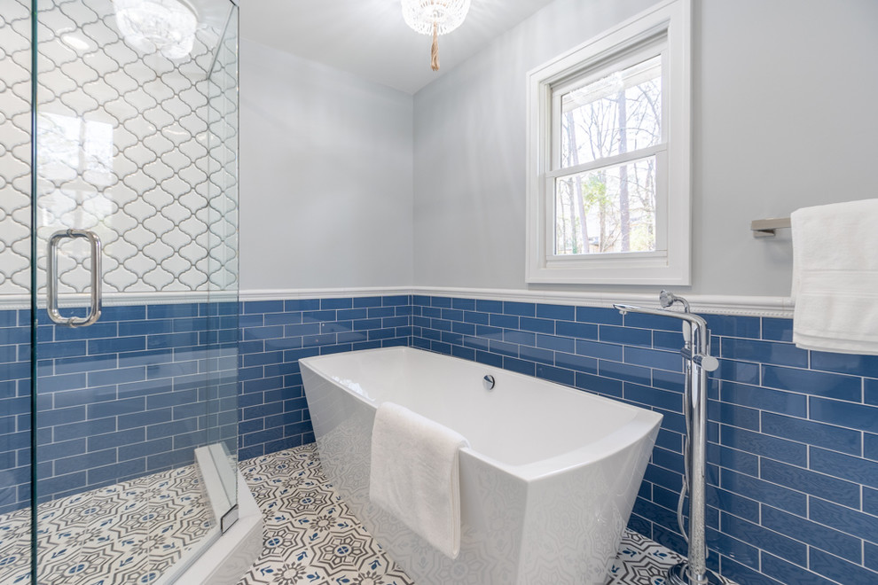 Cette image montre une salle de bain principale méditerranéenne de taille moyenne avec un placard à porte shaker, des portes de placard grises, une baignoire indépendante, une douche d'angle, WC séparés, un carrelage bleu, des carreaux de porcelaine, un mur gris, carreaux de ciment au sol, un lavabo encastré, un plan de toilette en quartz modifié et une cabine de douche à porte battante.