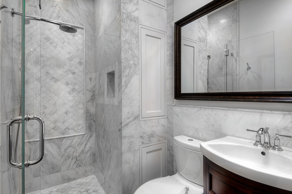 Example of a mid-sized transitional white tile and stone tile marble floor alcove shower design in San Francisco with furniture-like cabinets, dark wood cabinets, a one-piece toilet, gray walls, an integrated sink and a hinged shower door