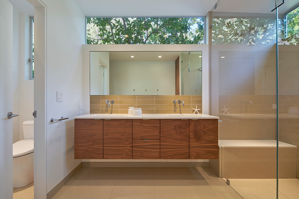 Cette image montre une grande salle de bain minimaliste en bois brun avec un placard à porte plane, WC à poser, un carrelage beige, un mur blanc, un lavabo encastré, un plan de toilette en quartz modifié et une cabine de douche à porte battante.