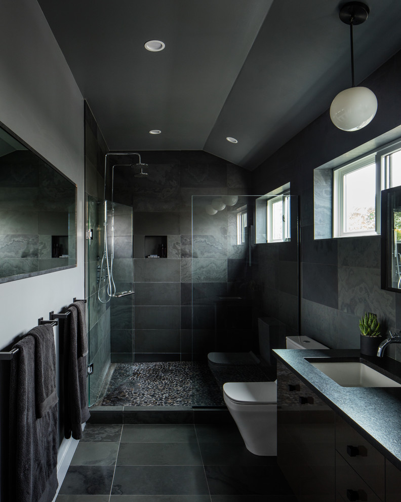На фото: главная ванная комната среднего размера в стиле модернизм с плоскими фасадами, черными фасадами, двойным душем, унитазом-моноблоком, черной плиткой, плиткой из сланца, серыми стенами, полом из керамогранита, врезной раковиной, столешницей из искусственного камня, черным полом и душем с распашными дверями с