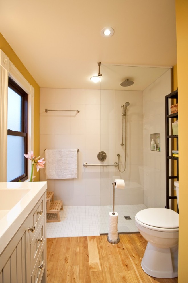 Cette photo montre une salle de bain principale tendance de taille moyenne avec un plan vasque, un placard à porte shaker, des portes de placard grises, une douche à l'italienne, WC à poser, un carrelage blanc, des carreaux de céramique, un mur jaune et parquet clair.