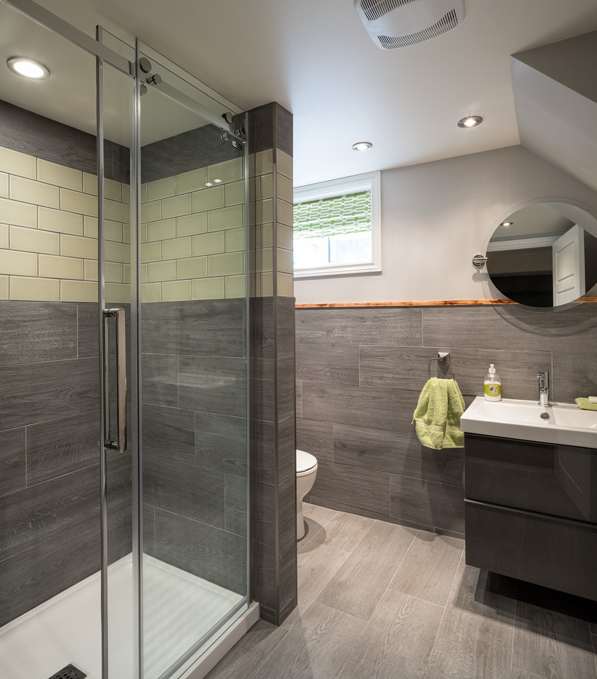 Photo of a medium sized traditional shower room bathroom in Ottawa with a console sink, flat-panel cabinets, grey cabinets, an alcove shower, a two-piece toilet, grey tiles, ceramic tiles, grey walls and ceramic flooring.