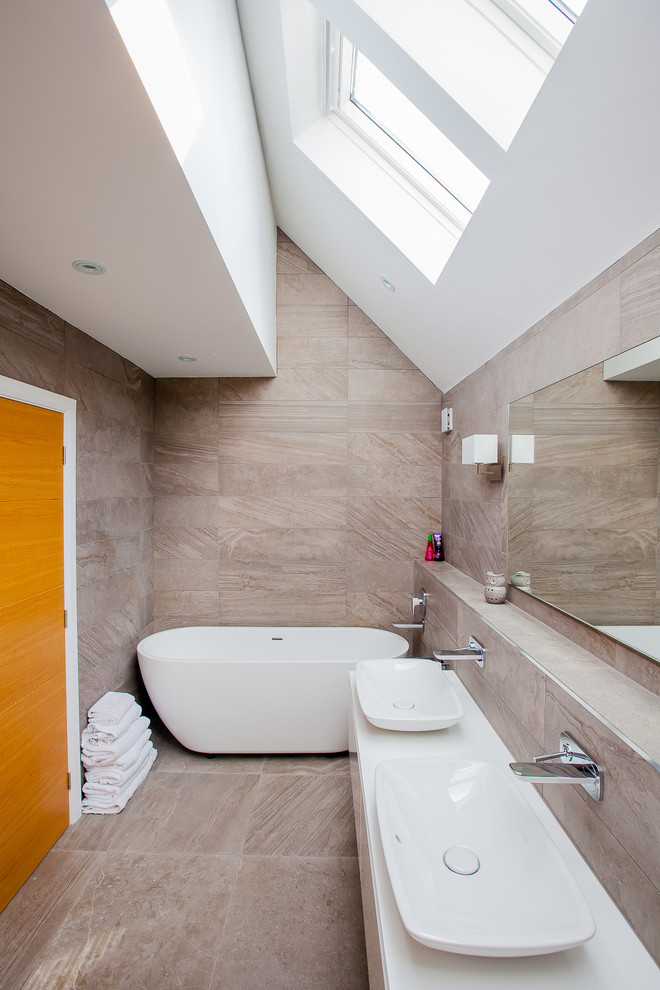 На фото: главная ванная комната в современном стиле с отдельно стоящей ванной, настольной раковиной и бежевой плиткой