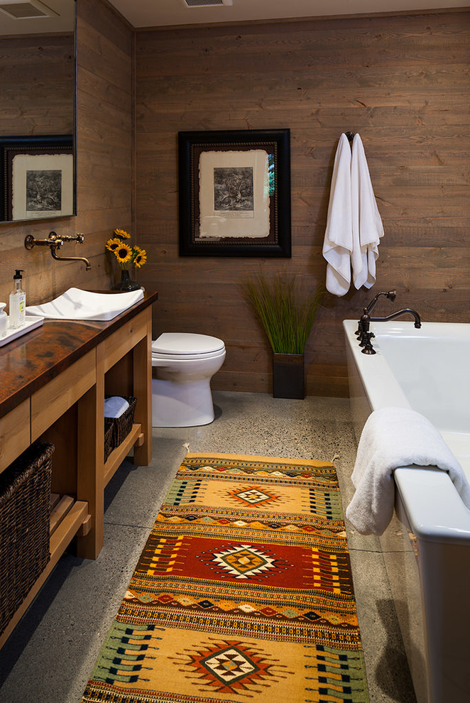 Foto på ett mellanstort rustikt badrum, med öppna hyllor, ett fristående badkar, bruna väggar, betonggolv, ett fristående handfat, bänkskiva i koppar och skåp i ljust trä