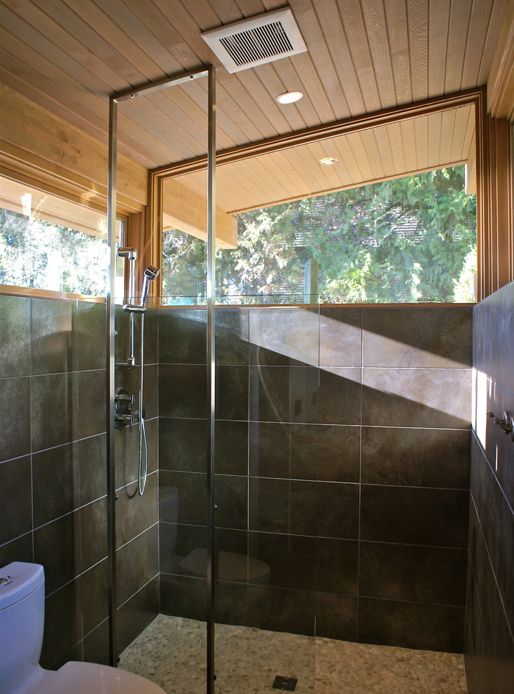Modelo de cuarto de baño actual con ducha abierta, baldosas y/o azulejos grises, suelo de baldosas tipo guijarro, ducha abierta y ventanas