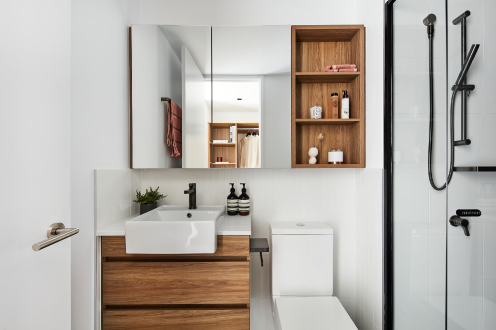 Réalisation d'une douche en alcôve design en bois brun avec un placard à porte plane, un mur blanc, une vasque, un plan de toilette blanc et meuble simple vasque.