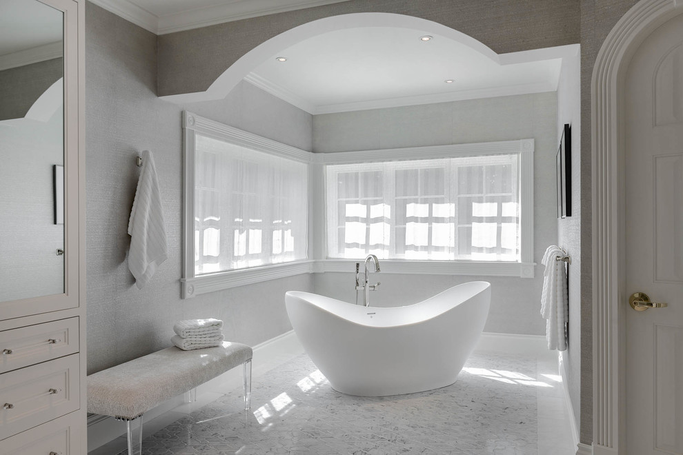 На фото: большая главная ванная комната в классическом стиле с фасадами в стиле шейкер, белыми фасадами, отдельно стоящей ванной, серыми стенами, мраморным полом, врезной раковиной, мраморной столешницей, серым полом и белой столешницей с