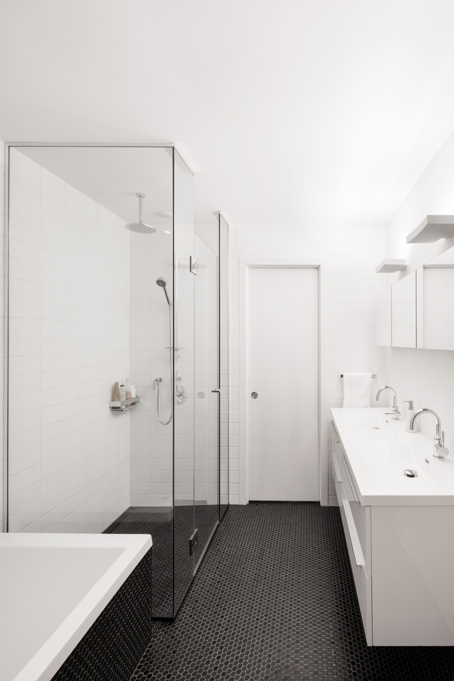 Inspiration for a medium sized contemporary ensuite bathroom in Montreal with flat-panel cabinets, white cabinets, a built-in bath, an alcove shower, a one-piece toilet, black tiles, mosaic tiles, white walls, an integrated sink and solid surface worktops.