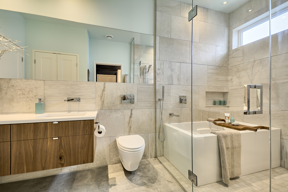 Design ideas for a medium sized contemporary ensuite bathroom in Montreal with flat-panel cabinets, medium wood cabinets, a freestanding bath, a shower/bath combination, a wall mounted toilet, beige tiles, ceramic tiles, blue walls, concrete flooring, a submerged sink and engineered stone worktops.