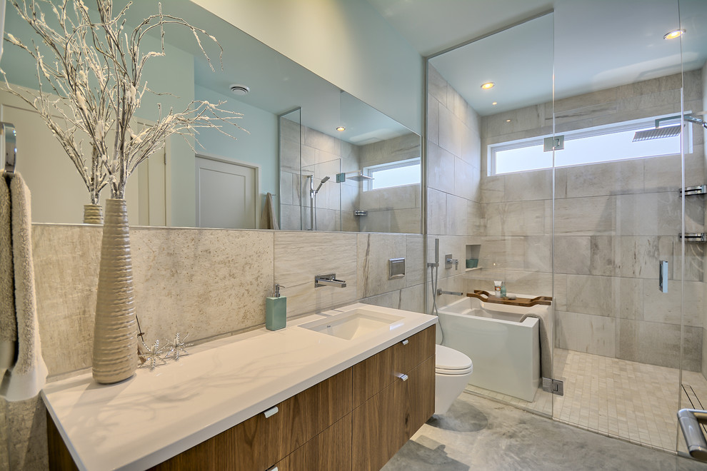 Exempel på ett mellanstort modernt en-suite badrum, med släta luckor, skåp i mellenmörkt trä, ett fristående badkar, en dusch/badkar-kombination, en vägghängd toalettstol, beige kakel, keramikplattor, blå väggar, betonggolv, ett undermonterad handfat och bänkskiva i kvarts