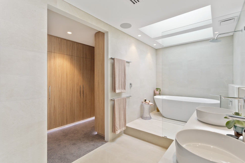 Cette photo montre une salle de bain tendance avec une baignoire indépendante, un carrelage gris, un mur beige, une vasque, un sol beige, un plan de toilette gris et meuble double vasque.