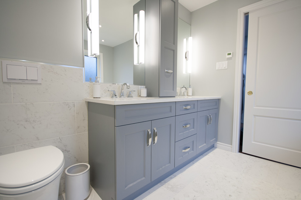 Inspiration for a medium sized classic ensuite bathroom in Ottawa with shaker cabinets, grey cabinets, a submerged bath, an alcove shower, a wall mounted toilet, white tiles, porcelain tiles, grey walls, porcelain flooring, a submerged sink, engineered stone worktops, white floors, a hinged door and white worktops.