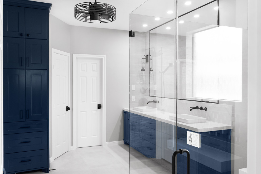 Inredning av ett modernt mellanstort vit vitt en-suite badrum, med luckor med infälld panel, blå skåp, en kantlös dusch, en toalettstol med separat cisternkåpa, grå kakel, keramikplattor, grå väggar, klinkergolv i porslin, ett fristående handfat, bänkskiva i kvarts, grått golv och med dusch som är öppen