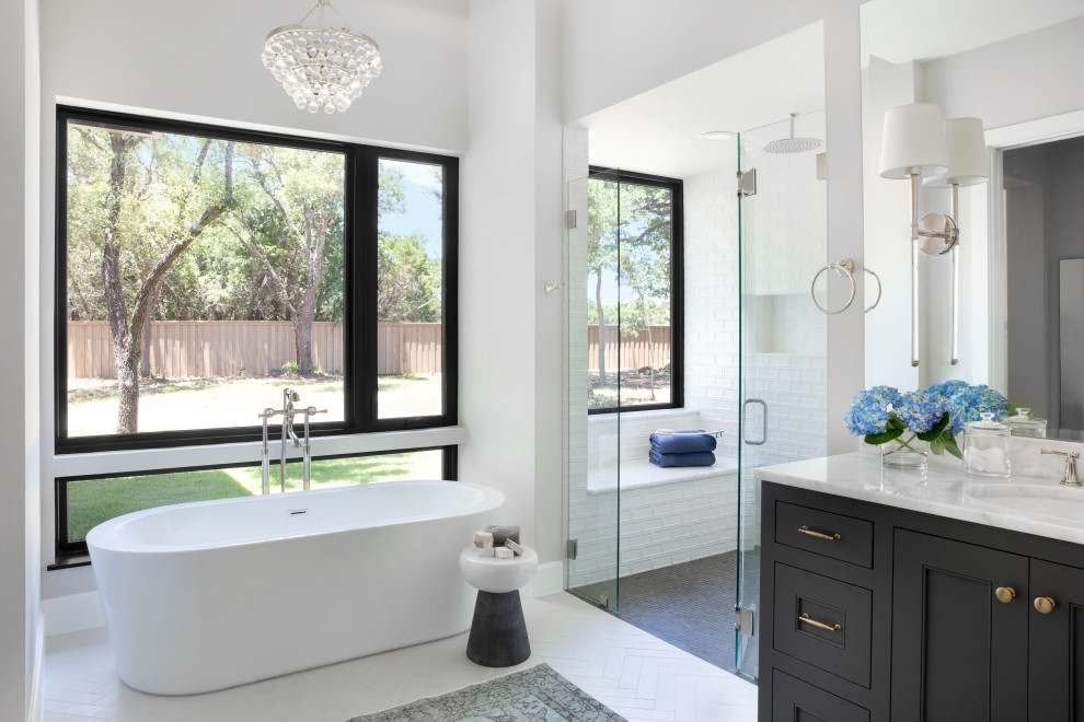 This is an example of a traditional bathroom in Austin with recessed-panel cabinets, black cabinets, a freestanding bath, white walls, a submerged sink, white floors and white worktops.