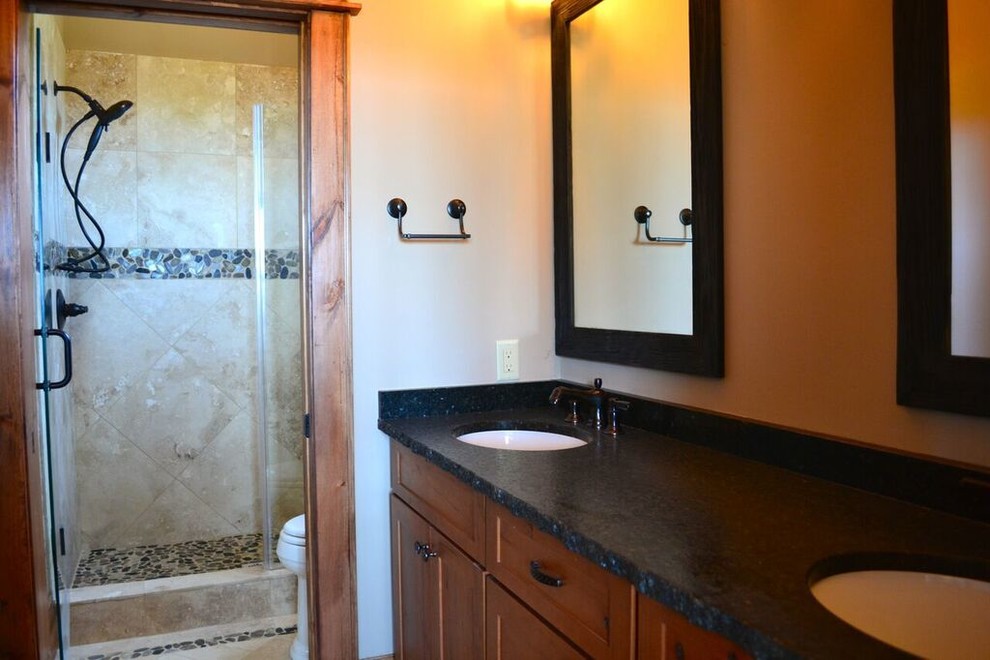 Foto di una stanza da bagno con doccia rustica di medie dimensioni con lavabo sottopiano, ante con riquadro incassato, ante in legno scuro, doccia alcova e pareti beige