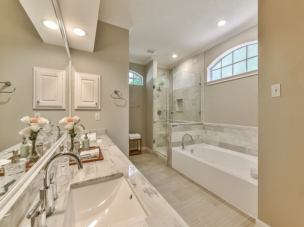 Example of a mid-sized transitional master gray tile and marble tile ceramic tile and beige floor bathroom design in Houston with louvered cabinets, white cabinets, beige walls, an undermount sink, marble countertops, a hinged shower door and white countertops