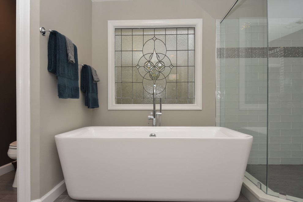 Пример оригинального дизайна: главная ванная комната среднего размера в стиле модернизм с фасадами в стиле шейкер, серыми фасадами, отдельно стоящей ванной, унитазом-моноблоком, серой плиткой, керамогранитной плиткой, серыми стенами, полом из керамогранита, врезной раковиной, столешницей из искусственного кварца и душем в нише