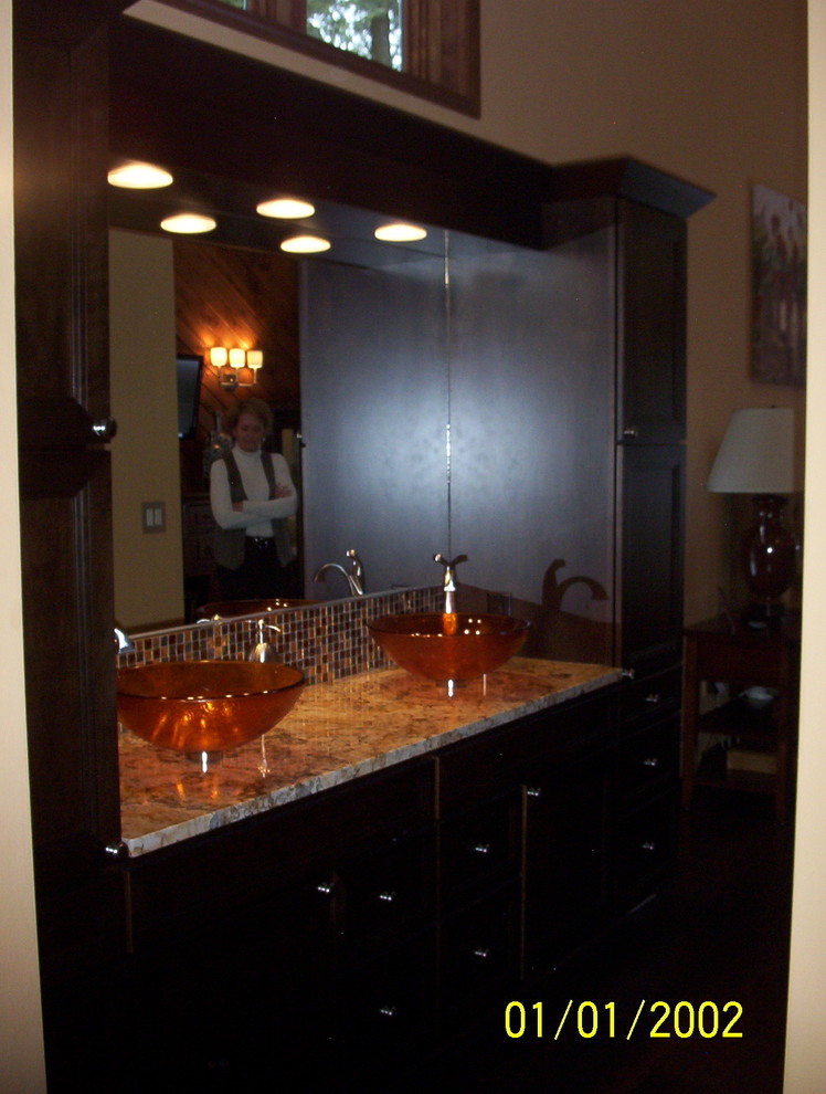 Inredning av ett modernt en-suite badrum, med ett fristående handfat, släta luckor, skåp i mörkt trä, granitbänkskiva, en dusch i en alkov, flerfärgad kakel och stenkakel