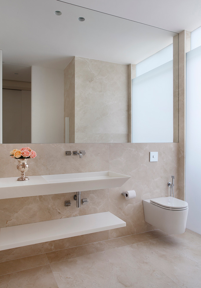 Modelo de cuarto de baño actual con lavabo integrado, armarios abiertos, sanitario de pared y baldosas y/o azulejos beige