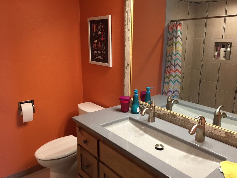 Ispirazione per una stanza da bagno chic con ante a filo, ante in legno chiaro, doccia alcova, WC monopezzo, pareti arancioni, lavabo integrato e top in cemento