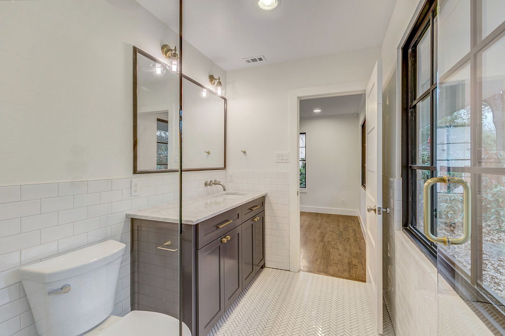 Medium sized traditional ensuite bathroom in Dallas with shaker cabinets, black cabinets, a built-in shower, a one-piece toilet, white tiles, metro tiles, white walls, mosaic tile flooring, a submerged sink, marble worktops, white floors and a hinged door.