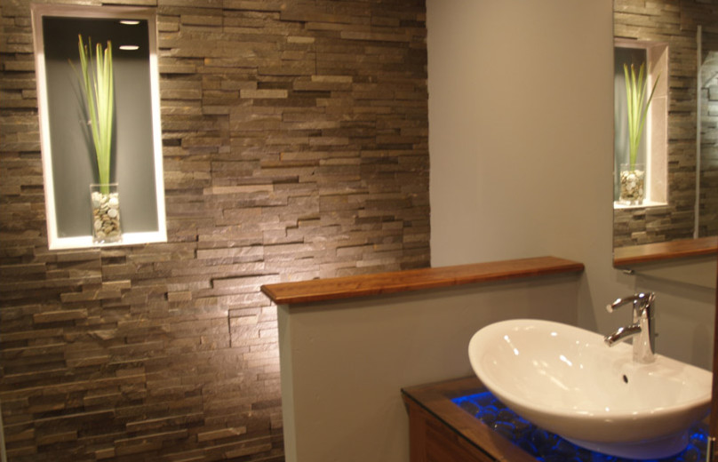 Foto di una stanza da bagno contemporanea con ante in legno scuro, piastrelle grigie, piastrelle in pietra, pareti beige, lavabo a bacinella e top in vetro