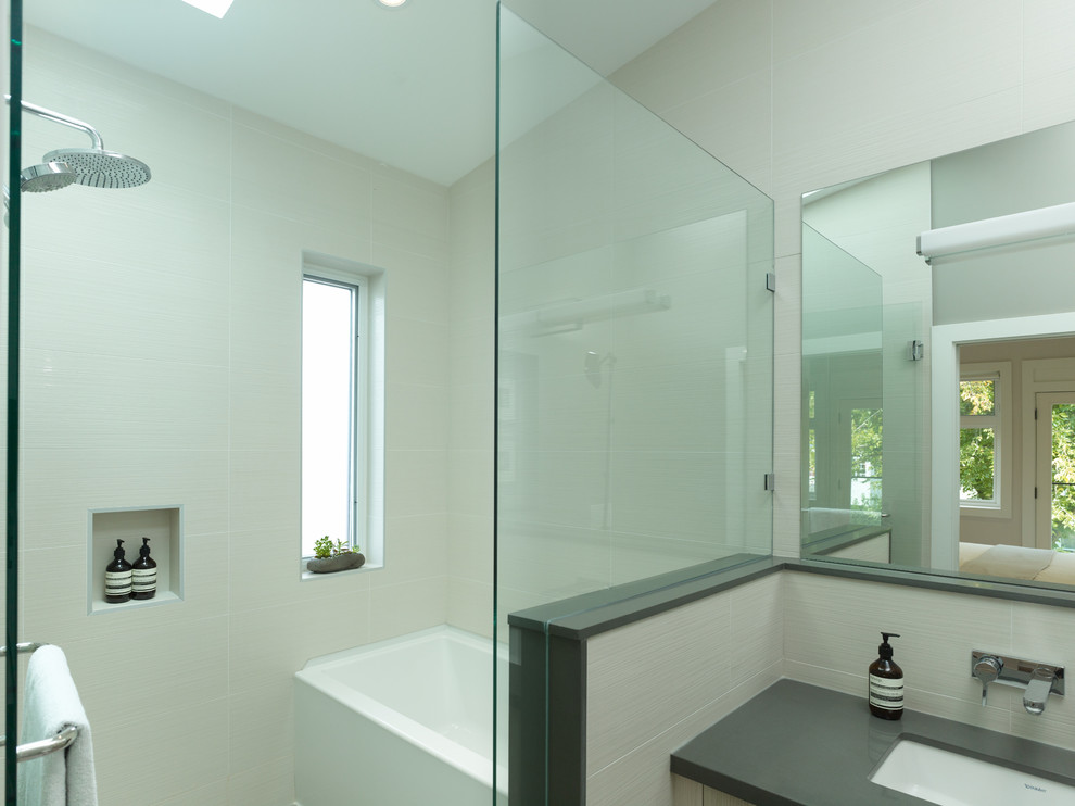 Cette photo montre une salle de bain tendance en bois clair avec un lavabo encastré, un placard à porte plane, un plan de toilette en granite, WC suspendus, un carrelage blanc, des carreaux de céramique, un mur gris et un sol en carrelage de céramique.