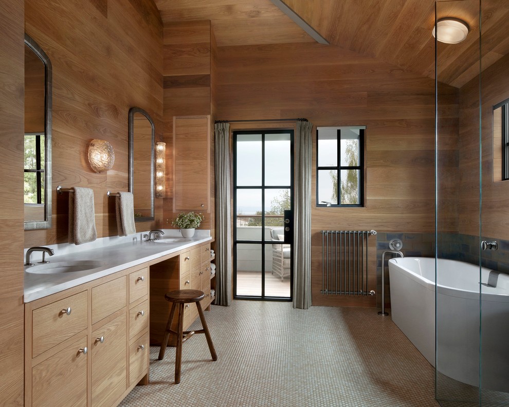 Diseño de cuarto de baño principal de estilo americano con armarios con paneles lisos, puertas de armario de madera clara, bañera exenta y lavabo bajoencimera