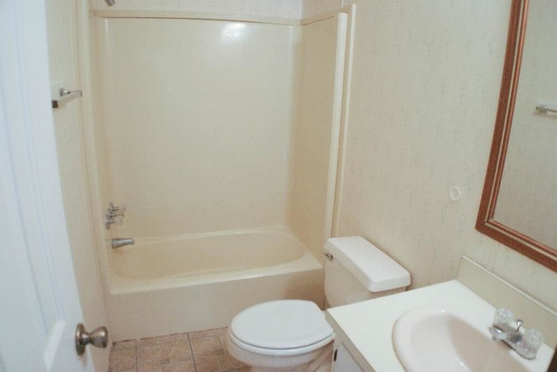 Idées déco pour une salle de bain classique de taille moyenne pour enfant avec un placard à porte plane, des portes de placard blanches, un combiné douche/baignoire, WC séparés, un carrelage blanc, un mur beige, un sol en vinyl, un lavabo posé et un plan de toilette en stratifié.