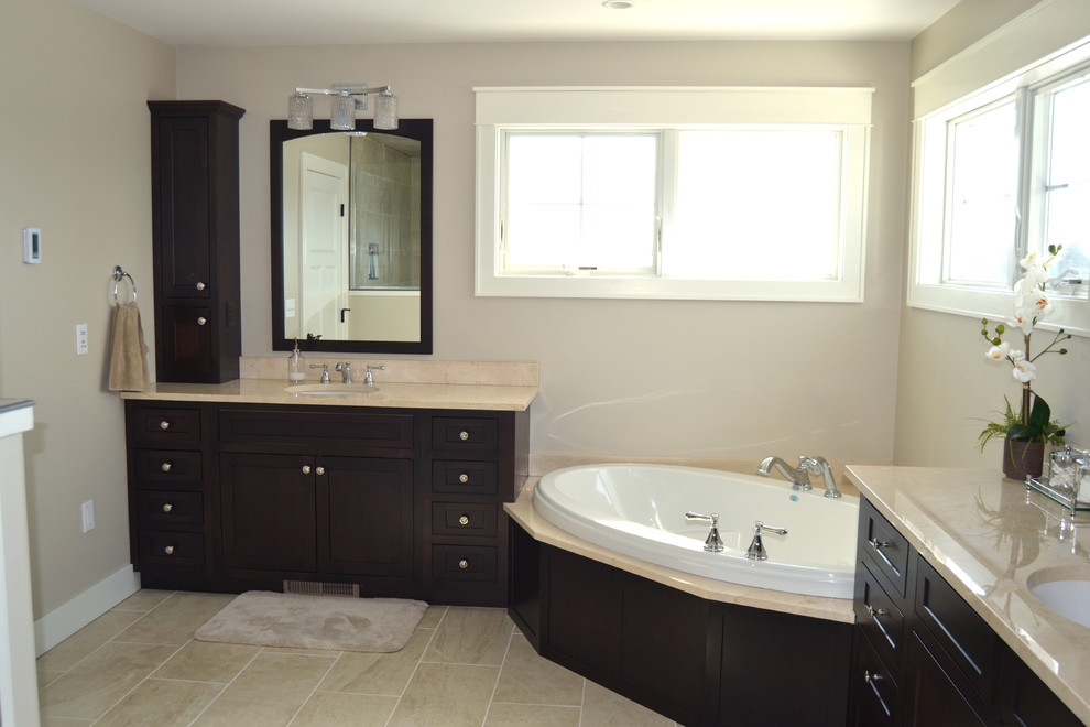 Cette photo montre une grande salle de bain chic en bois foncé avec un lavabo encastré, un placard avec porte à panneau encastré, une baignoire d'angle et une douche d'angle.