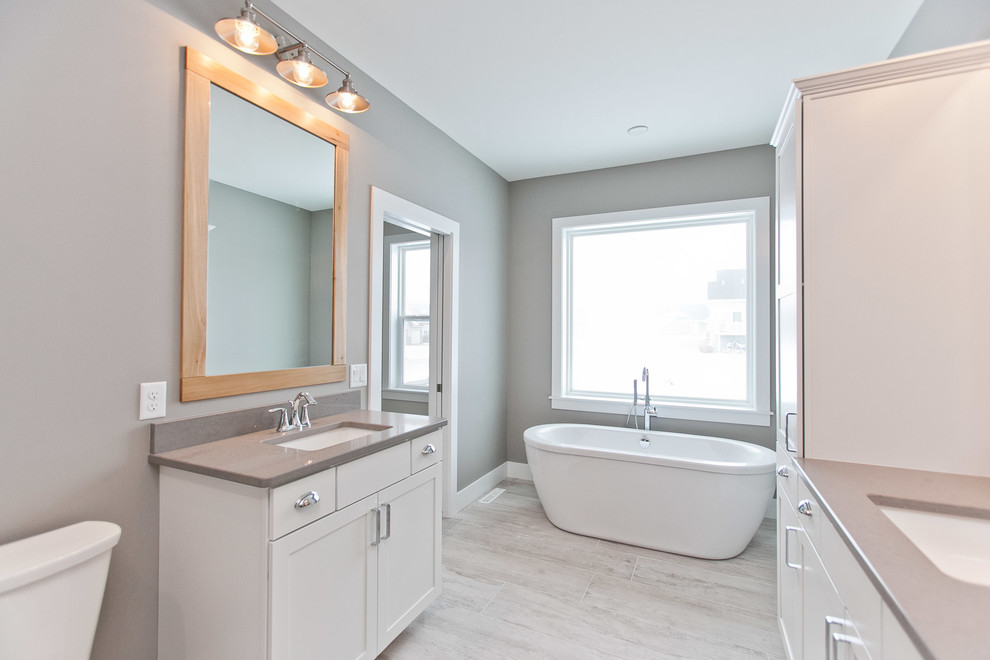Inspiration for a large transitional master light wood floor and gray floor bathroom remodel in Cedar Rapids with shaker cabinets, white cabinets, gray walls, an undermount sink, quartz countertops and a hinged shower door
