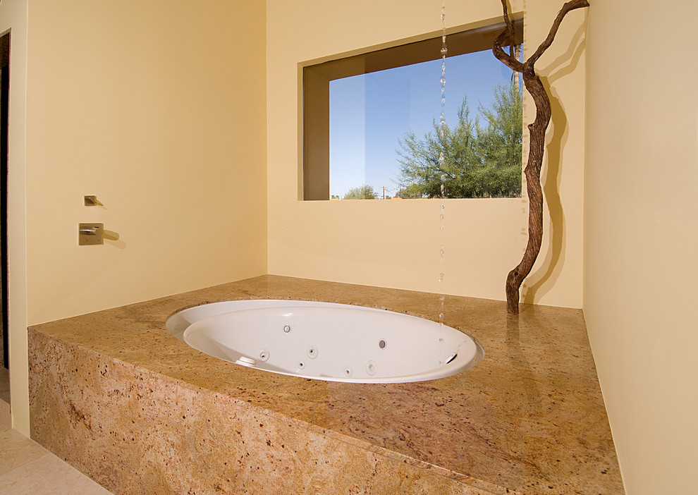 На фото: огромная главная ванная комната в современном стиле с полновстраиваемой ванной, бежевой плиткой, плиткой из листового камня, желтыми стенами, полом из известняка, столешницей из гранита и бежевым полом с