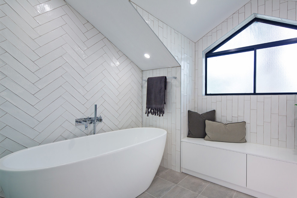 Photo of a large contemporary ensuite bathroom in Sydney with flat-panel cabinets, white cabinets, a freestanding bath, a built-in shower, a one-piece toilet, white tiles, ceramic tiles, white walls, ceramic flooring, a built-in sink, marble worktops, grey floors and a hinged door.