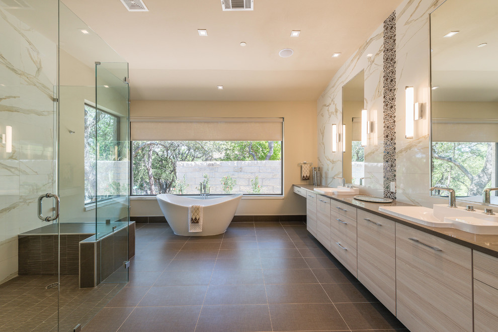 На фото: огромная главная ванная комната в современном стиле с накладной раковиной, плоскими фасадами, светлыми деревянными фасадами, отдельно стоящей ванной, коричневой плиткой и бежевыми стенами
