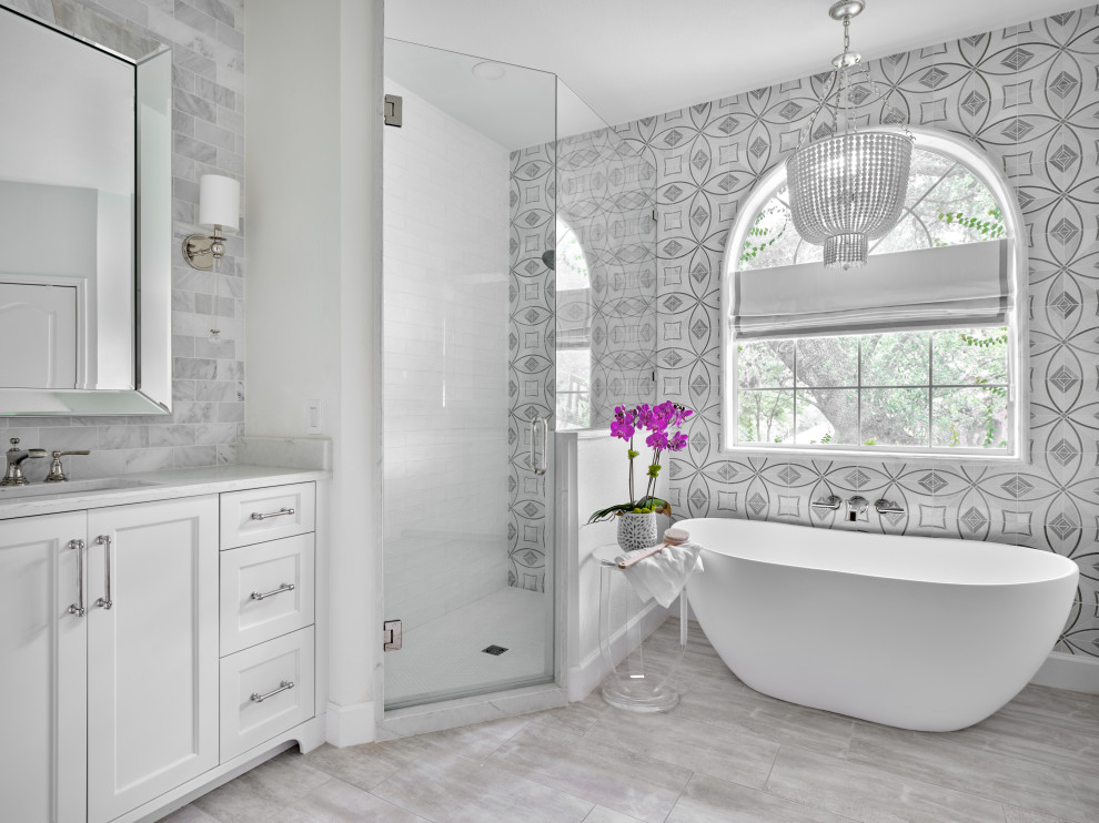 Inspiration for a medium sized classic ensuite bathroom in Austin with shaker cabinets, white cabinets, a freestanding bath, a corner shower, marble tiles, white walls, porcelain flooring, a submerged sink, engineered stone worktops, grey floors, a hinged door, white worktops, a built in vanity unit, grey tiles and white tiles.