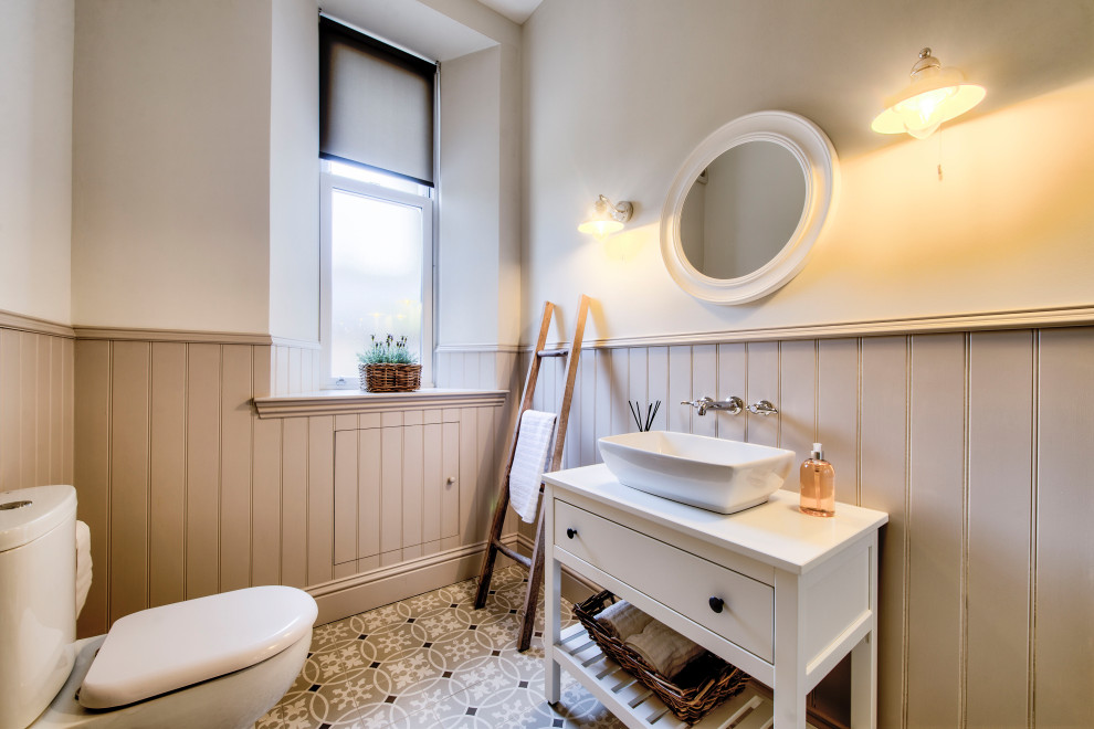 На фото: ванная комната в стиле неоклассика (современная классика) с белыми фасадами, раздельным унитазом, разноцветными стенами, полом из мозаичной плитки, настольной раковиной, разноцветным полом, белой столешницей и плоскими фасадами