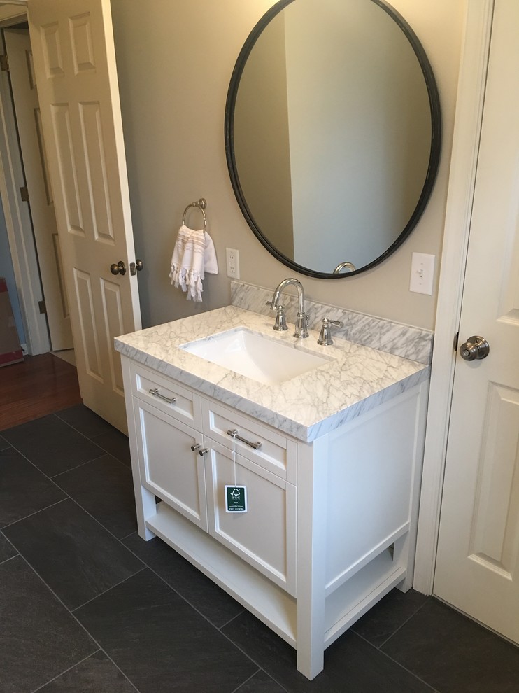 Example of a mid-sized classic 3/4 porcelain tile and gray tile porcelain tile and black floor bathroom design in Other with shaker cabinets, white cabinets, white walls, an undermount sink, marble countertops and a two-piece toilet
