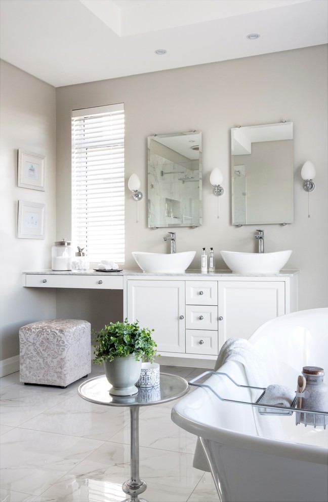 Large traditional ensuite bathroom in Other with shaker cabinets, white cabinets, a freestanding bath, a double shower, a wall mounted toilet, beige walls, marble flooring, a vessel sink and engineered stone worktops.