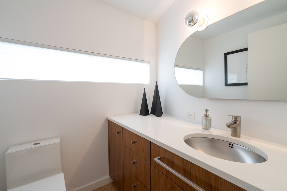 シアトルにある小さなモダンスタイルのおしゃれな浴室 (フラットパネル扉のキャビネット、中間色木目調キャビネット、一体型トイレ	、白い壁、淡色無垢フローリング、珪岩の洗面台、白い洗面カウンター) の写真