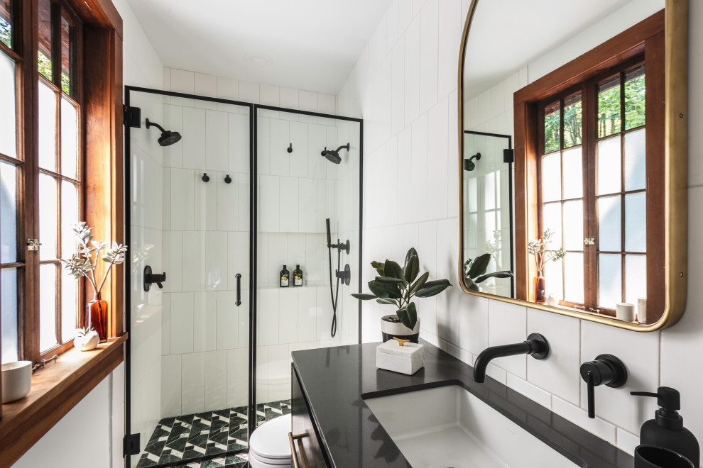Trendy white tile multicolored floor and single-sink alcove shower photo in Seattle with flat-panel cabinets, dark wood cabinets, an undermount sink, a hinged shower door and black countertops
