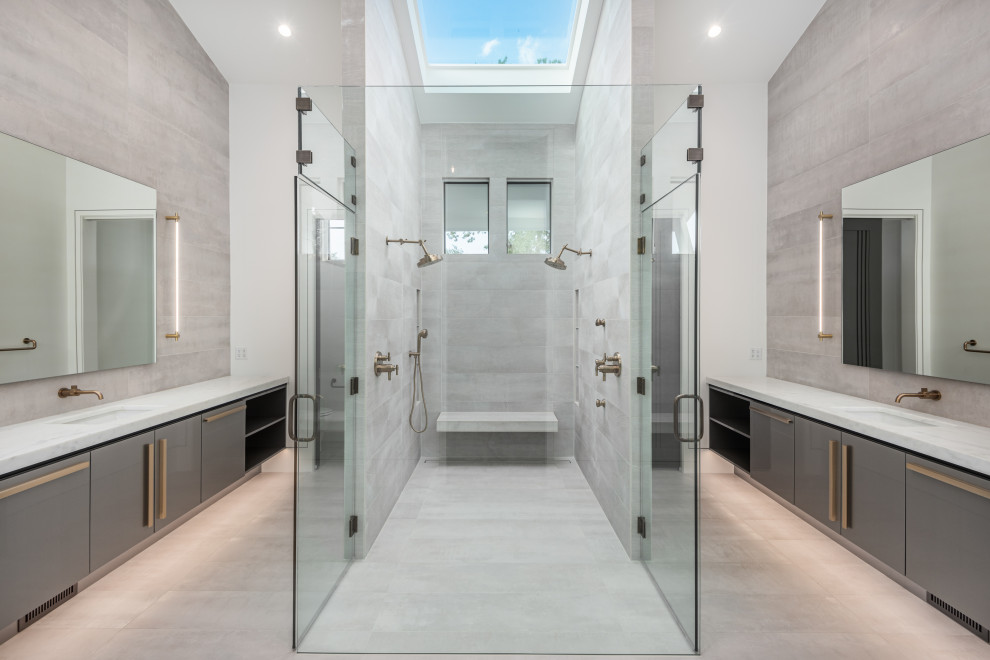 Пример оригинального дизайна: огромная главная ванная комната в стиле модернизм с плоскими фасадами, серыми фасадами, душем без бортиков, раздельным унитазом, серой плиткой, керамогранитной плиткой, белыми стенами, полом из керамогранита, врезной раковиной, мраморной столешницей, серым полом, открытым душем, белой столешницей, нишей, тумбой под две раковины, подвесной тумбой и сводчатым потолком