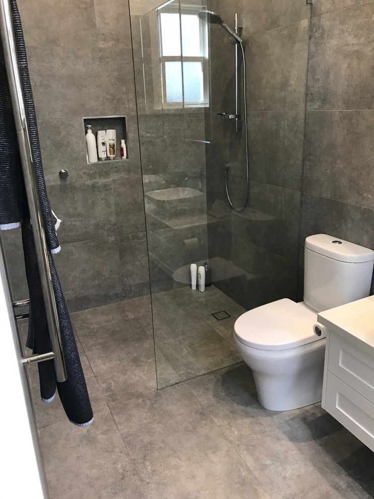 This is an example of a small victorian ensuite bathroom in Melbourne with recessed-panel cabinets, white cabinets, a walk-in shower, a two-piece toilet, grey tiles, porcelain tiles, porcelain flooring, a built-in sink, granite worktops, an open shower, white worktops, a single sink and a floating vanity unit.