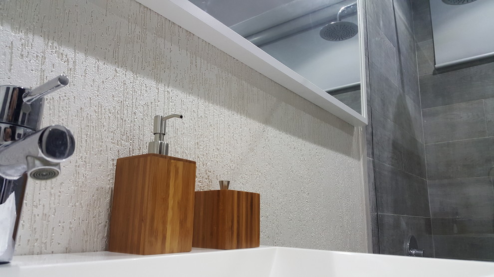 Cette photo montre une petite salle de bain moderne avec des portes de placard grises, une douche ouverte, WC à poser, un carrelage gris, des carreaux de porcelaine, un mur blanc, un sol en carrelage de céramique, un lavabo intégré et un plan de toilette en quartz.