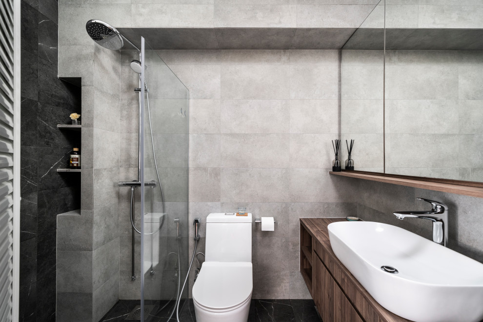 Пример оригинального дизайна: ванная комната в современном стиле с плоскими фасадами, темными деревянными фасадами, душем в нише, серой плиткой, настольной раковиной, черным полом и коричневой столешницей