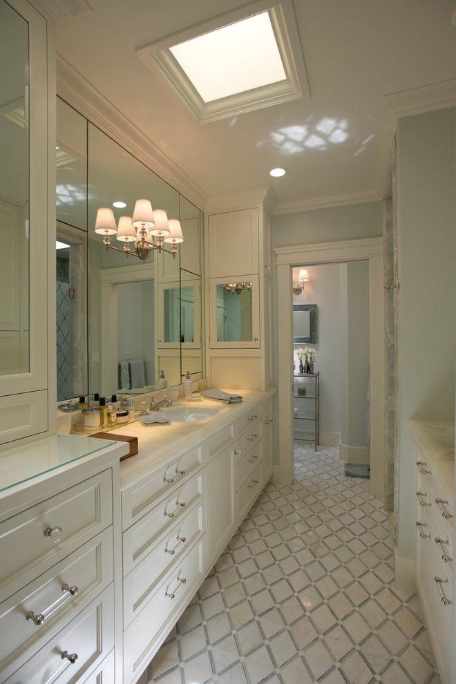 Cette image montre une salle de bain traditionnelle avec un lavabo encastré, un placard avec porte à panneau encastré, des portes de placard blanches et un mur gris.