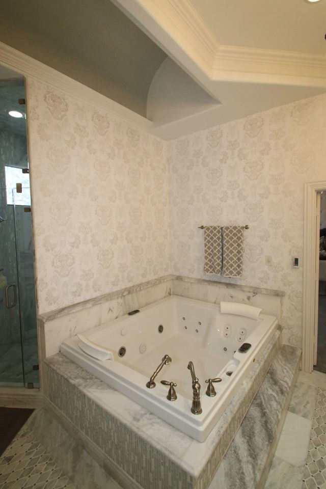 Exemple d'une grande salle de bain principale chic avec un placard avec porte à panneau surélevé, des portes de placard blanches, une baignoire posée, une douche d'angle, un mur blanc, un sol en marbre, un lavabo encastré et un plan de toilette en marbre.