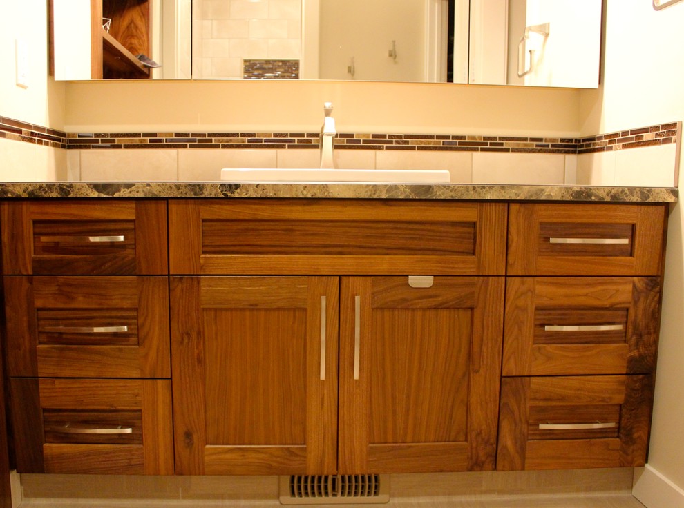 Foto på ett litet amerikanskt badrum med dusch, med skåp i shakerstil, skåp i mellenmörkt trä, en toalettstol med hel cisternkåpa, brun kakel, mosaik, beige väggar, vinylgolv, ett nedsänkt handfat och laminatbänkskiva