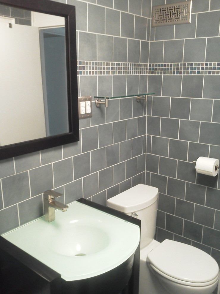 ワシントンD.C.にある高級な中くらいなトラディショナルスタイルのおしゃれなバスルーム (浴槽なし) (グレーのタイル、フラットパネル扉のキャビネット、黒いキャビネット、磁器タイル、ガラスの洗面台、アルコーブ型浴槽、シャワー付き浴槽	、分離型トイレ、グレーの壁、磁器タイルの床、一体型シンク、グレーの床、シャワーカーテン) の写真