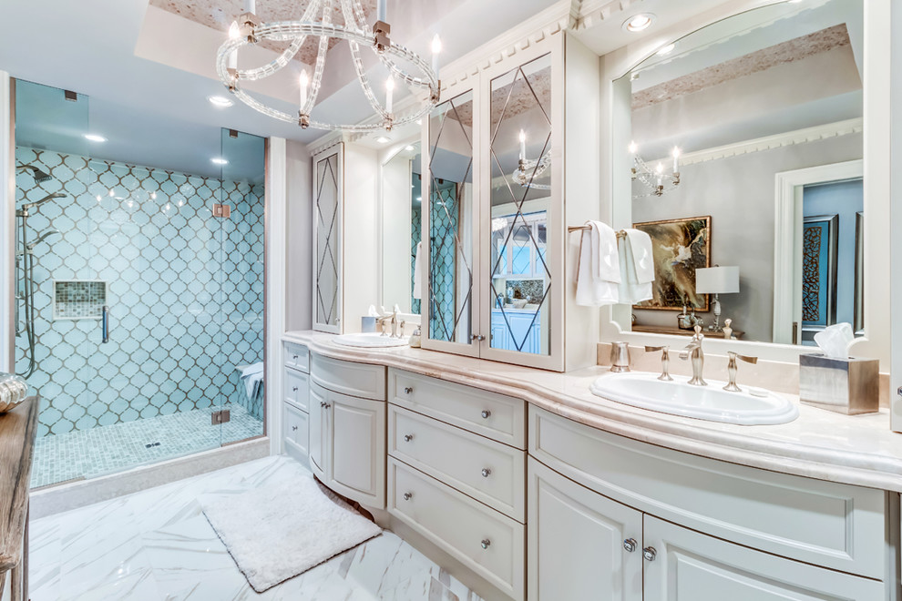 Foto på ett stort vintage badrum, med dusch med gångjärnsdörr, luckor med upphöjd panel, vita skåp, en dusch i en alkov, blå kakel, keramikplattor, beige väggar, ett nedsänkt handfat och vitt golv