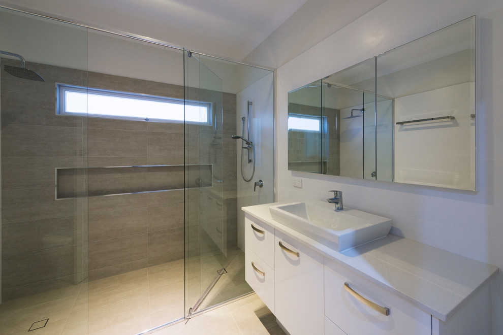 Modern inredning av ett stort en-suite badrum, med ett piedestal handfat, släta luckor, vita skåp, bänkskiva i akrylsten, en dubbeldusch, grå kakel, keramikplattor, vita väggar och klinkergolv i porslin